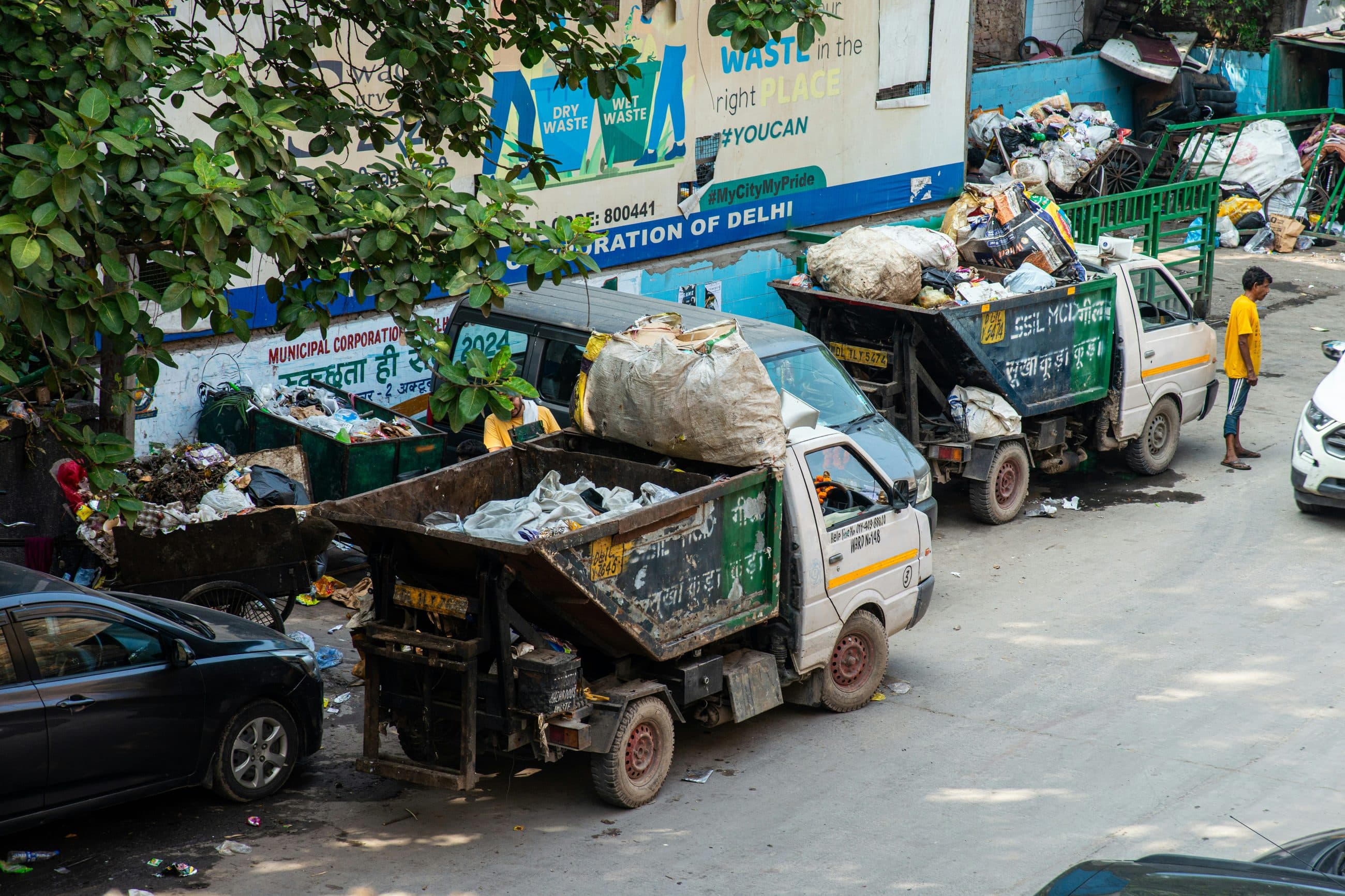 Waste collection vehicles loading refuse on a city street